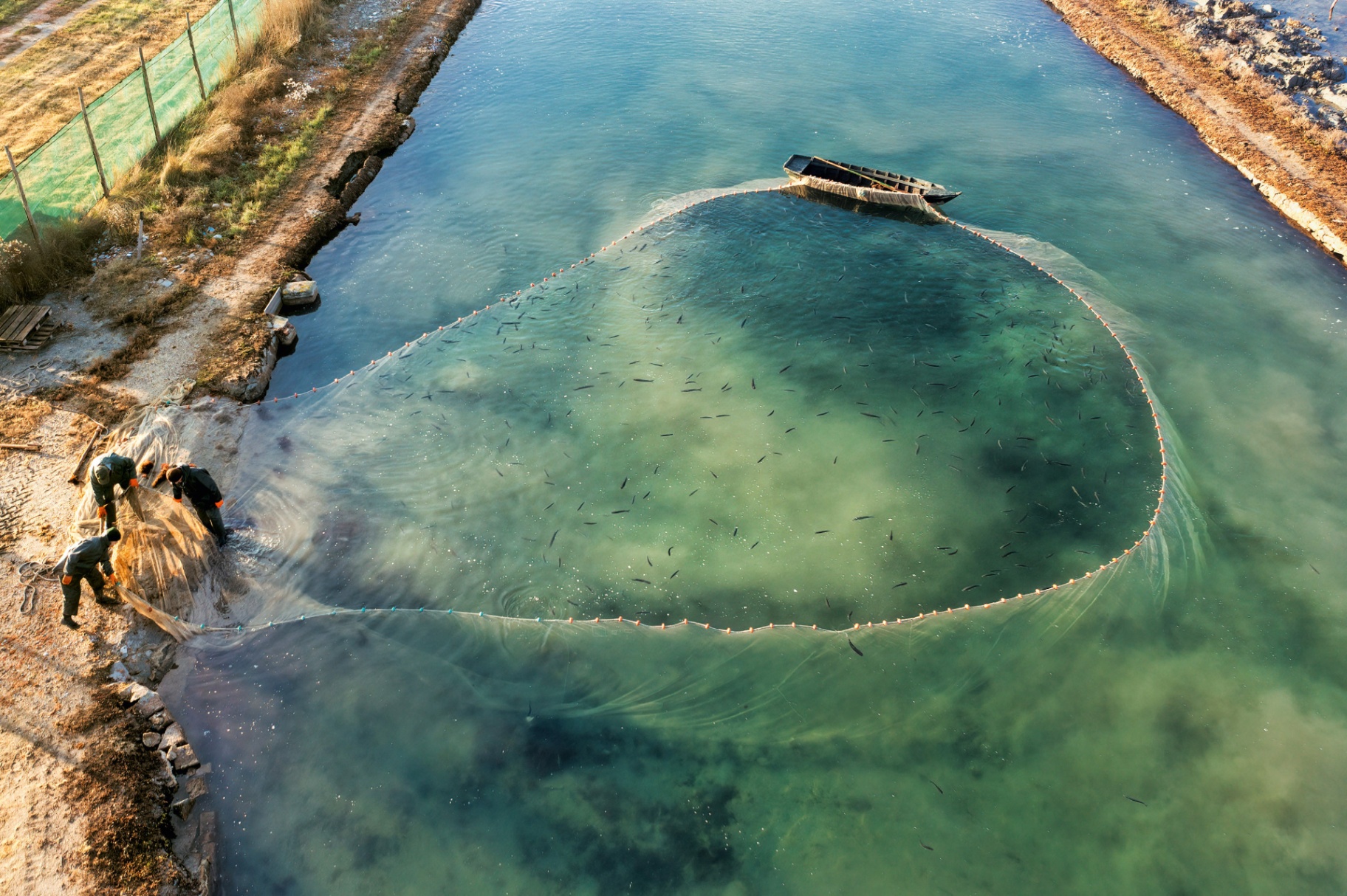 Floating thatched huts on a wetland lagoon at sunset — regenerative living in harmony with water