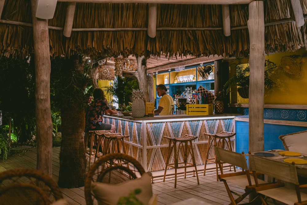 Thatched-roof cocktail bar with bamboo stools at night