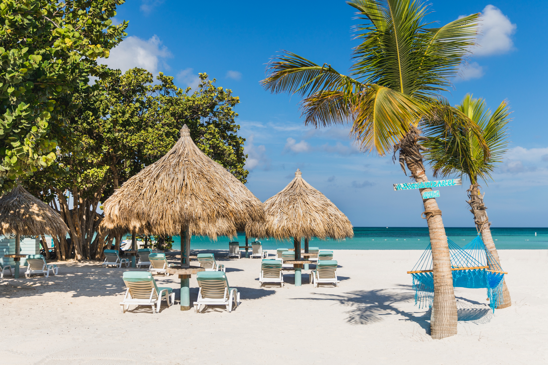 Boardwalk beach with palapas and turquoise hammock