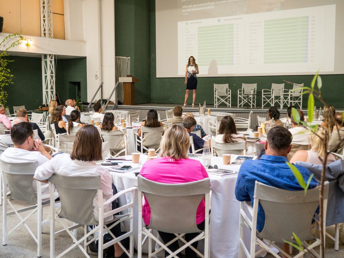 A speaker presenting research to delegates seated at round tables