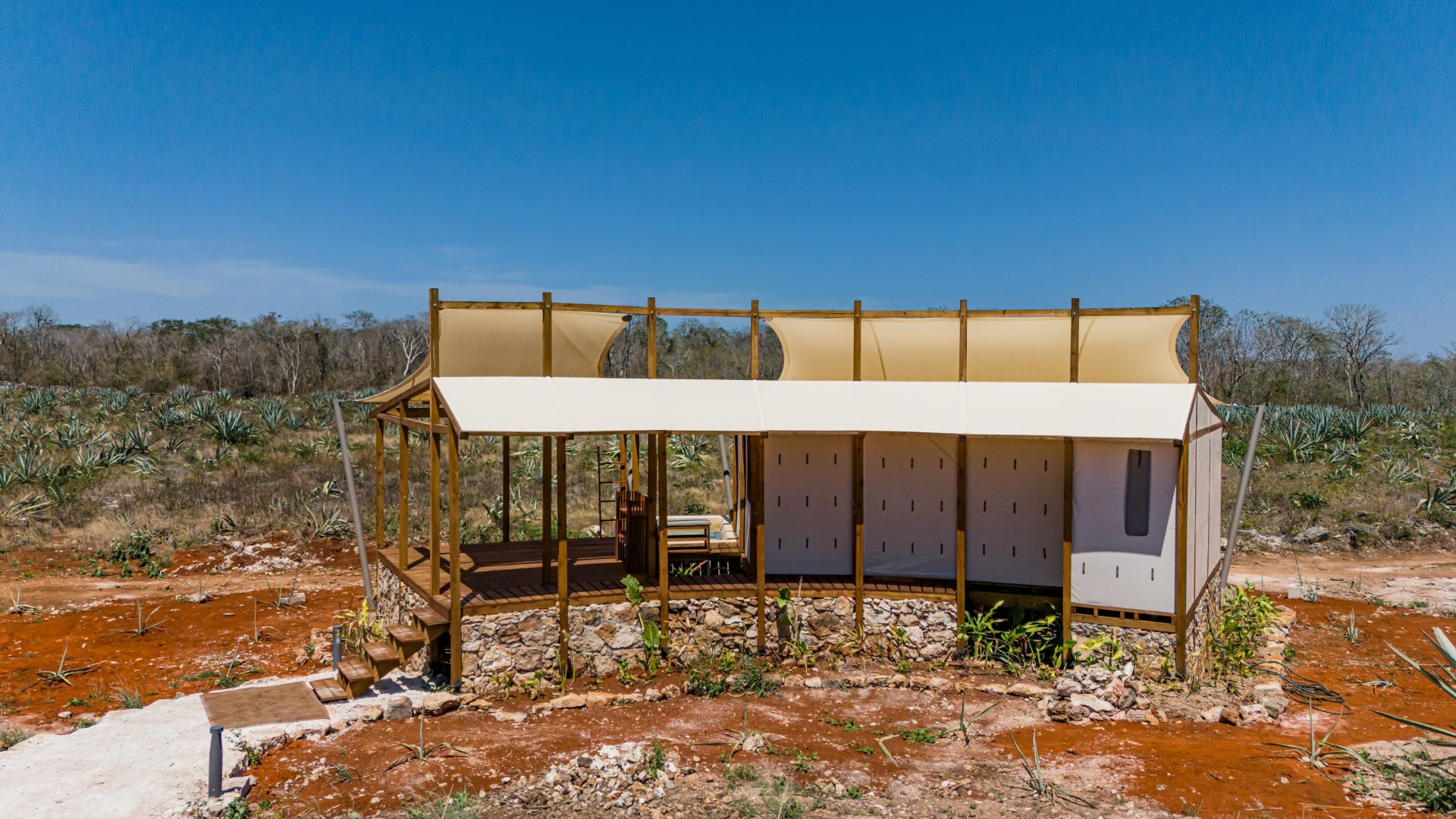 Tented suites built with reclaimed wood, stone and hand-woven textures — architecture that merges into the land.
